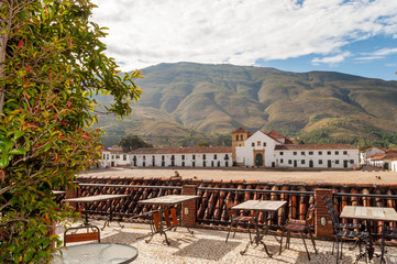 Plant and restaurant tables in front of Villa de Leyva main square with andes mountains in the...