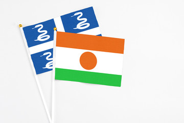 Niger and Martinique stick flags on white background. High quality fabric, miniature national flag. Peaceful global concept.White floor for copy space.