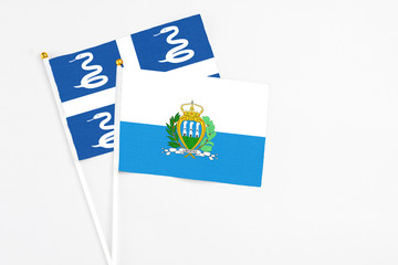 San Marino and Martinique stick flags on white background. High quality fabric, miniature national flag. Peaceful global concept.White floor for copy space.