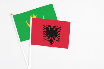 Albania and Mauritania stick flags on white background. High quality fabric, miniature national flag. Peaceful global concept.White floor for copy space.