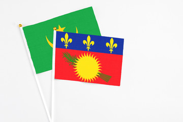 Guadeloupe and Mauritania stick flags on white background. High quality fabric, miniature national flag. Peaceful global concept.White floor for copy space.