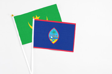 Guam and Mauritania stick flags on white background. High quality fabric, miniature national flag. Peaceful global concept.White floor for copy space.