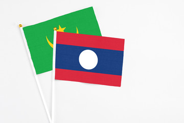 Laos and Mauritania stick flags on white background. High quality fabric, miniature national flag. Peaceful global concept.White floor for copy space.