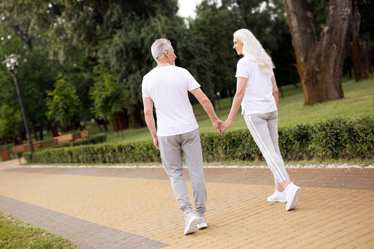 Romantic elderly couple walking hand in hand stock photo