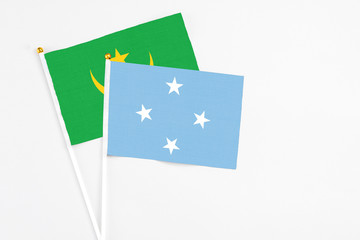 Micronesia and Mauritania stick flags on white background. High quality fabric, miniature national flag. Peaceful global concept.White floor for copy space.