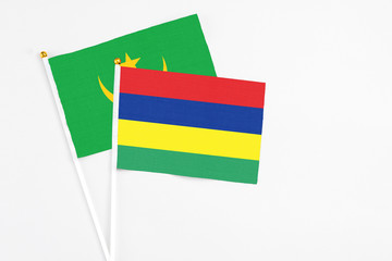 Mauritius and Mauritania stick flags on white background. High quality fabric, miniature national flag. Peaceful global concept.White floor for copy space.