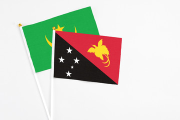 Papua New Guinea and Mauritania stick flags on white background. High quality fabric, miniature national flag. Peaceful global concept.White floor for copy space.