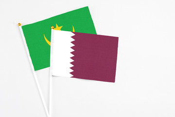 Qatar and Mauritania stick flags on white background. High quality fabric, miniature national flag. Peaceful global concept.White floor for copy space.
