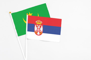 Serbia and Mauritania stick flags on white background. High quality fabric, miniature national flag. Peaceful global concept.White floor for copy space.