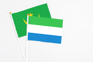 Sierra Leone and Mauritania stick flags on white background. High quality fabric, miniature national flag. Peaceful global concept.White floor for copy space.