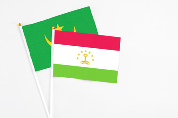 Tajikistan and Mauritania stick flags on white background. High quality fabric, miniature national flag. Peaceful global concept.White floor for copy space.