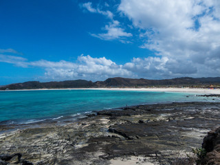 An idyllic beach in Lombok, Pantai Nambung in Indonesia. The beach is partially stony and partially sandy. Water has many shades of blue. Perfect day for relaxation on the beach.