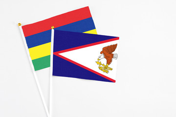 American Samoa and Mauritius stick flags on white background. High quality fabric, miniature national flag. Peaceful global concept.White floor for copy space.