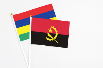 Angola and Mauritius stick flags on white background. High quality fabric, miniature national flag. Peaceful global concept.White floor for copy space.