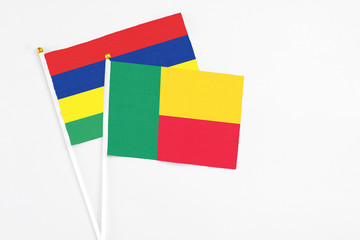 Benin and Mauritius stick flags on white background. High quality fabric, miniature national flag. Peaceful global concept.White floor for copy space.