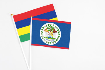 Belize and Mauritius stick flags on white background. High quality fabric, miniature national flag. Peaceful global concept.White floor for copy space.