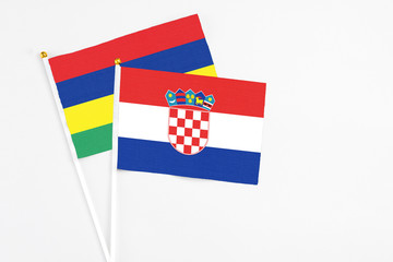 Croatia and Mauritius stick flags on white background. High quality fabric, miniature national flag. Peaceful global concept.White floor for copy space.