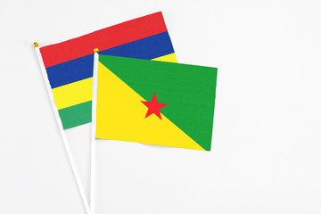 French Guiana and Mauritius stick flags on white background. High quality fabric, miniature national flag. Peaceful global concept.White floor for copy space.