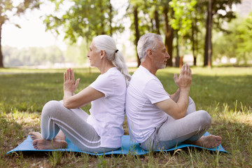 Pleased man and woman meditating back to back stock photo