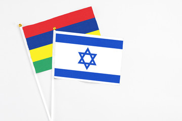 Israel and Mauritius stick flags on white background. High quality fabric, miniature national flag. Peaceful global concept.White floor for copy space.