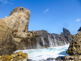 Wave waterfall on Pantai Nambung, Lombok, Indonesia.The water crushes on the rocks on shore, breaching through them, creating a temporary waterfall. The rock formation looks very sharp and dangerous