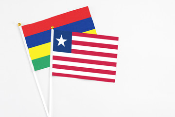 Liberia and Mauritius stick flags on white background. High quality fabric, miniature national flag. Peaceful global concept.White floor for copy space.