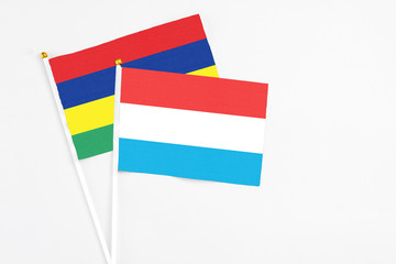 Luxembourg and Mauritius stick flags on white background. High quality fabric, miniature national flag. Peaceful global concept.White floor for copy space.
