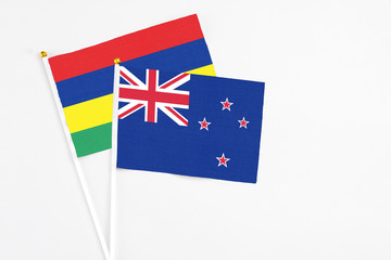 New Zealand and Mauritius stick flags on white background. High quality fabric, miniature national flag. Peaceful global concept.White floor for copy space.