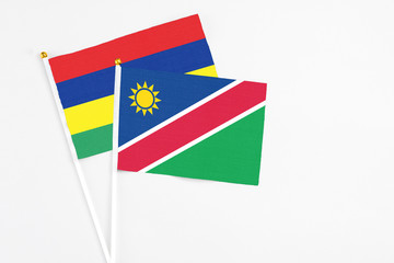 Namibia and Mauritius stick flags on white background. High quality fabric, miniature national flag. Peaceful global concept.White floor for copy space.