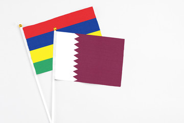 Qatar and Mauritius stick flags on white background. High quality fabric, miniature national flag. Peaceful global concept.White floor for copy space.
