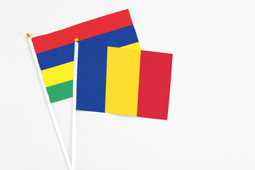 Romania and Mauritius stick flags on white background. High quality fabric, miniature national flag. Peaceful global concept.White floor for copy space.