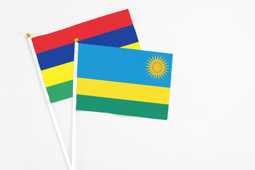 Rwanda and Mauritius stick flags on white background. High quality fabric, miniature national flag. Peaceful global concept.White floor for copy space.