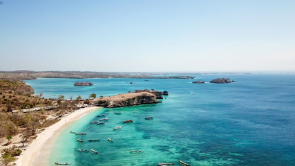 Obraz premium Przestrzenny, dronowy film z widokiem na idylliczną Różową Plażę na Lombok w Indonezji. Wiele łodzi dryfuje po spokojnej tafli morza. Dziewiczy, ukryty klejnot. Idealne miejsce na spokojne, relaksujące wakacje