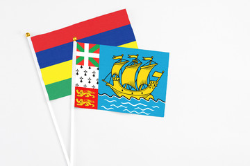 Saint Pierre And Miquelon and Mauritius stick flags on white background. High quality fabric, miniature national flag. Peaceful global concept.White floor for copy space.