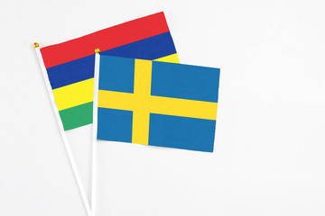 Sweden and Mauritius stick flags on white background. High quality fabric, miniature national flag. Peaceful global concept.White floor for copy space.