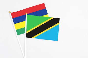 Tanzania and Mauritius stick flags on white background. High quality fabric, miniature national flag. Peaceful global concept.White floor for copy space.