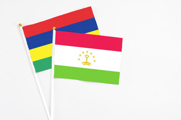 Tajikistan and Mauritius stick flags on white background. High quality fabric, miniature national flag. Peaceful global concept.White floor for copy space.