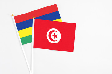 Tunisia and Mauritius stick flags on white background. High quality fabric, miniature national flag. Peaceful global concept.White floor for copy space.