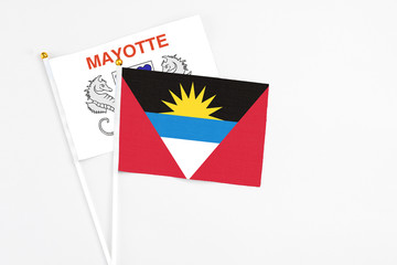 Antigua and Barbuda and Mayotte stick flags on white background. High quality fabric, miniature national flag. Peaceful global concept.White floor for copy space.