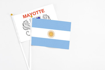 Argentina and Mayotte stick flags on white background. High quality fabric, miniature national flag. Peaceful global concept.White floor for copy space.
