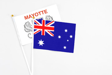 Fototapeta premium Australia and Mayotte stick flags on white background. High quality fabric, miniature national flag. Peaceful global concept.White floor for copy space.