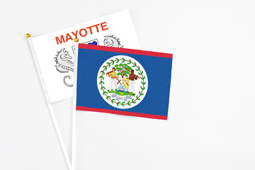Belize and Mayotte stick flags on white background. High quality fabric, miniature national flag. Peaceful global concept.White floor for copy space.
