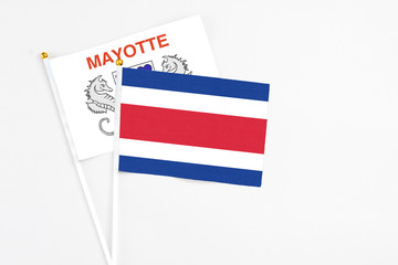 Costa Rica and Mayotte stick flags on white background. High quality fabric, miniature national flag. Peaceful global concept.White floor for copy space.