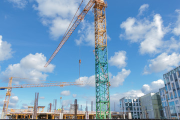 close u of construction site with crane in sunny day with blue sky and white clouds.