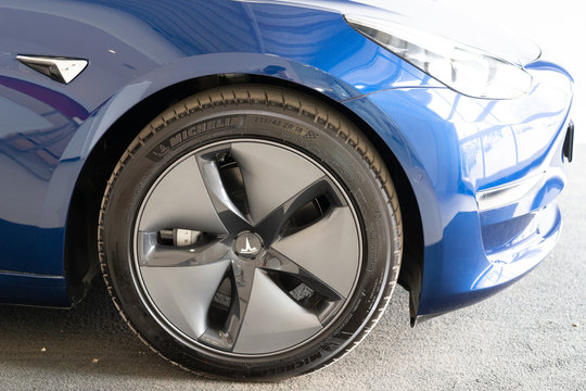Tesla aluminium rim plastic wheel hubcap of luxury electric blue Model 3 car logo parked