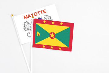 Grenada and Mayotte stick flags on white background. High quality fabric, miniature national flag. Peaceful global concept.White floor for copy space.