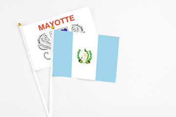 Guatemala and Mayotte stick flags on white background. High quality fabric, miniature national flag. Peaceful global concept.White floor for copy space.