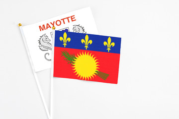 Guadeloupe and Mayotte stick flags on white background. High quality fabric, miniature national flag. Peaceful global concept.White floor for copy space.