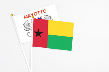 Guinea Bissau and Mayotte stick flags on white background. High quality fabric, miniature national flag. Peaceful global concept.White floor for copy space.