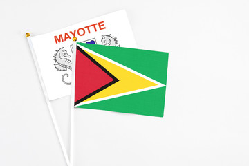 Guyana and Mayotte stick flags on white background. High quality fabric, miniature national flag. Peaceful global concept.White floor for copy space.